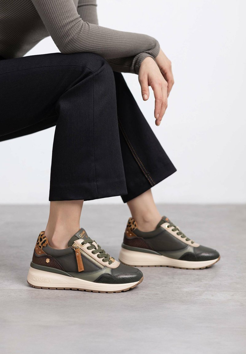 Zapatillas de cuero verde con detalles en beige, un cierre y estampado de leopardo en la parte trasera. La suela es gruesa y ligera.