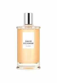 Genomskinlig glasparfymflaska med ribbad textur, silverlock och en vit etikett som visar "DAVID BECKHAM CLASSIC." Ljus bärnstenfärgade vätska inuti.