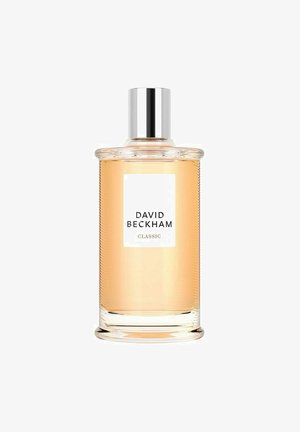Klart glas parfume flaske med ribbet tekstur, sølvlåg og en hvid etiket, der viser "DAVID BECKHAM CLASSIC." Lys amberfarvet væske indeni.