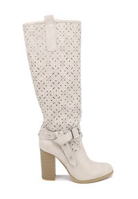 Stivali al ginocchio in pelle beige chiaro con motivi floreali intagliati, un tacco largo e una cinghia alla caviglia fissata con dettagli in metallo argentato.