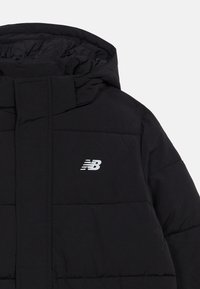 Juodas pūkinis švarkas su gaubtu ir priekinėmis kišenėmis, ant kairiojo krūtinės puikuojasi balta "New Balance" emblema.