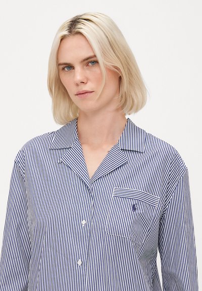 Camisa de pijama listrada em azul marinho e branco, com frente abotoada, colarinho em pico e um bolso no peito com um pequeno logotipo. Textura de tecido suave.