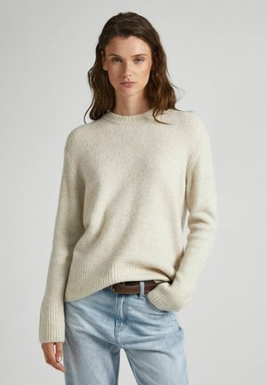Suéter de color beige claro, con cuello redondo, hecho de una suave mezcla de lana, con puños y dobladillo de canalé, combinado con unos pantalones de mezclilla azul claro y un cinturón de cuero marrón.
