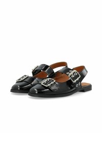 Čierne lakanové slingback topánky s okrúhlou špičkou, ktoré majú veľké strieborné pracky a otvorený dizajn vzadu. Plochej podrážky s dekoratívnymi akcentami.