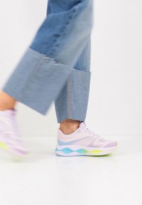 Ελαφρύ παπούτσι τρεξίματος σε παστέλ ροζ, μπλε και πράσινο. Διαθέτει επάνω μέρος από δίχτυ και υφασμένο πέλμα με κυματιστές λεπτομέρειες. Πόδι σε κίνηση.