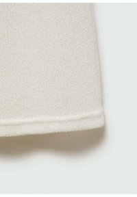 Tessuto a maglia di un beige chiaro e strutturato, con una finitura liscia, caratterizzato da un orlo pulito e un sottile dettaglio di cucitura lungo il bordo inferiore.