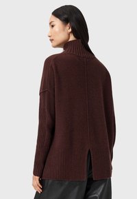 Bordeaux sweater med høj ribkant, dropped shoulders og ribbet kant. Har en slids bagpå for ekstra design detaljer. Blød tekstur.