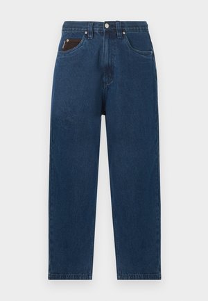 Otse säärega tumesinised teksapüksid kõrge vöökohaga ning väike must rahakott, mis paistab osaliselt esimesest paremast taskust välja.