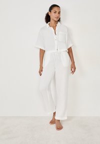 Witte katoenen tweedelige set bestaande uit een cropped button-down shirt en losse broek met een elastische tailleband en zakken.