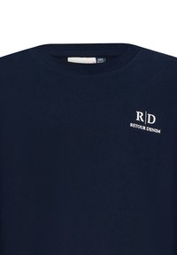 T-shirt in cotone blu navy con scollatura rotonda e un piccolo logo bianco con "R/D RETOUR DENIM" sulla parte superiore sinistra.