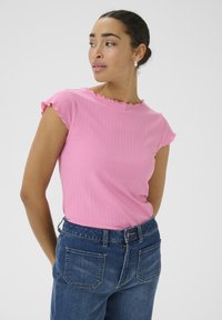 Rosa geripptes kurzärmeliges Oberteil mit gewelltem Ausschnitt, kombiniert mit Denim-Jeans. Der Stoff hat eine glatte Textur und ein figurbetontes Design.