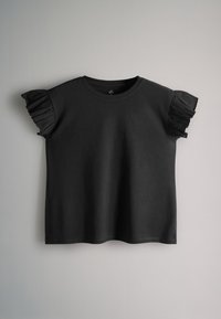 Sort top med korte ærmer, rund halsudskæring og plisserede flæsedetaljer på ærmerne, vist mod en ensfarvet lys baggrund.