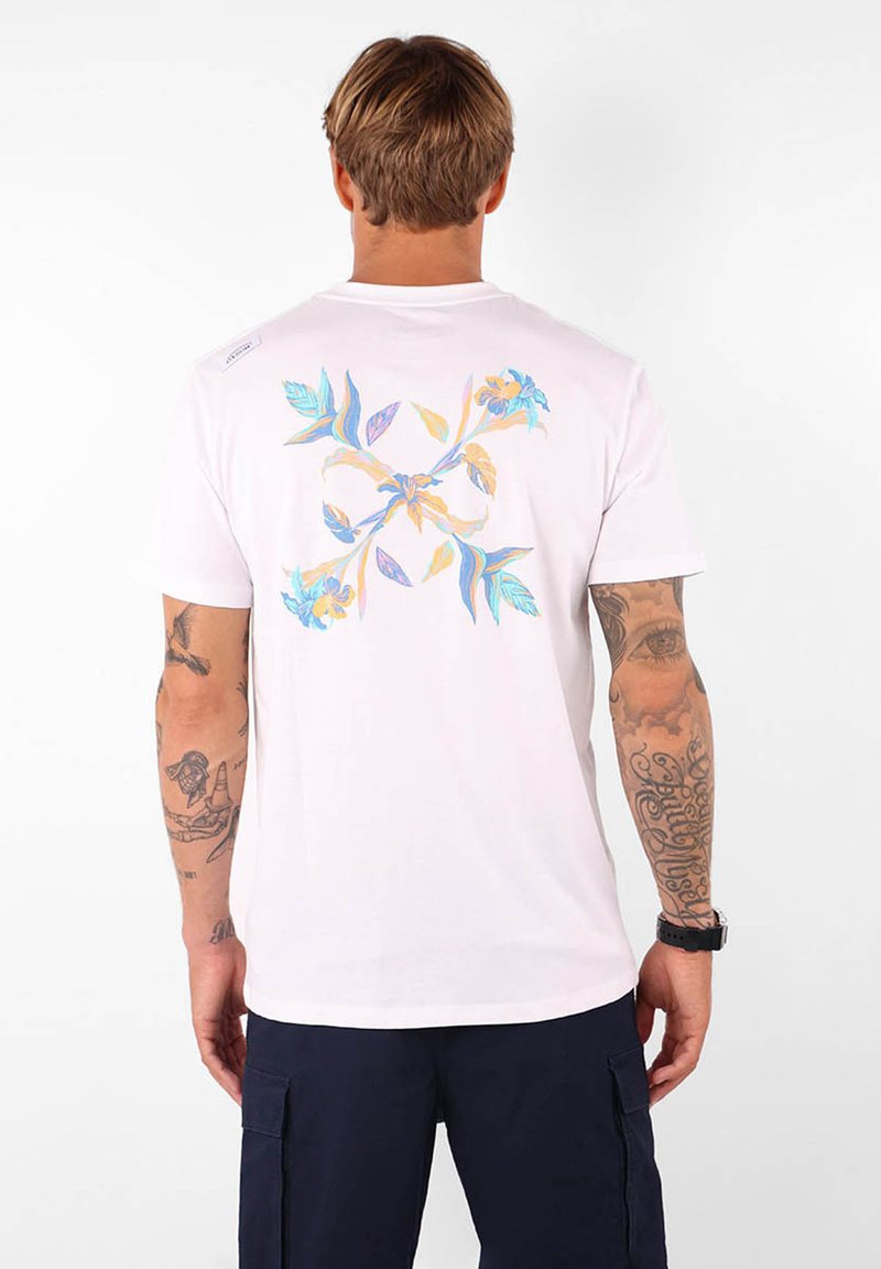 T-shirt en coton blanc avec un design floral coloré au dos, manches courtes et encolure ronde.