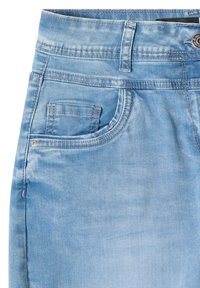 Gros plan d'un jean en denim bleu clair montrant la ceinture, le passant de ceinture, la poche avant, la poche à monnaie, le bouton et les coutures visibles.