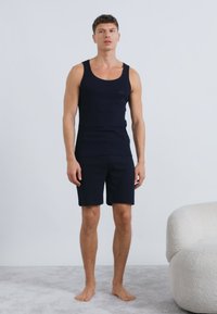 Čierny bavlnený set tielko a šortky. Tesný strih s hladkou textúrou. Má jednoduchý okrúhly výstrih bez viditeľných vzorov.