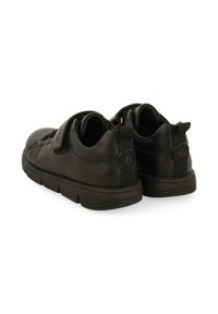 Zapatos de cuero negro con una textura suave, con una correa de velcro, punta redondeada y una suela de goma gruesa para mayor durabilidad.