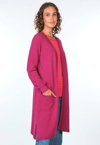Magenta langer Cardigan mit strukturiertem Muster, offenem Vorderteil, langen Ärmeln und zwei Seitentaschen, über einem rot-weißen gestreiften Oberteil.