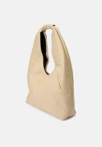Beige leather shoulder bag with a unique cut-out handle, smooth texture, and angular design, featuring subtle seam details and a lined interior.