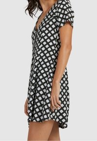 Robe noire à manches courtes, avec un col en V et des motifs floraux blancs. Le tissu semble léger et fluide, avec une coupe décontractée.