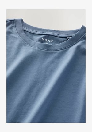 Svijetloplava pamuk majica s okruglim izrezom i kratkim rukavima. Ima glatku teksturu i naziv brenda "NEXT" otisnut unutar ovratnika.