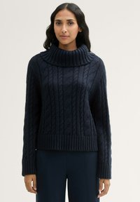 Marineblauer gestrickter Pullover mit hohem, umgeschlagenem Kragen, ausgestattet mit einem Zopfmuster sowie gerippten Bündchen und Saum.