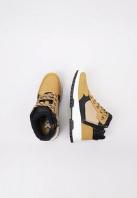 Zapatillas de media caña en marrón y negro con cuero texturizado, paneles de malla y suelas de goma blanca. Presenta punta redonda y cordones con patrón.