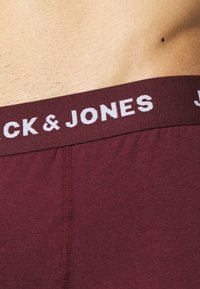Boxer-briefs bordeaux avec une texture douce, comportant une ceinture élastique blanche affichant "JACK & JONES" en lettres majuscules.