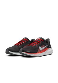 Chaussures de sport noires avec des lacets rouges, un dessus en maille respirante et un logo swoosh blanc. Dotées d'une semelle blanche rembourrée et d'une semelle extérieure en caoutchouc texturé.