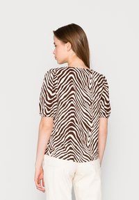 Blusa de manga curta em padrões de zebra castanho e creme, com um corte descontraído, apresentando um decote redondo e mangas ligeiramente bufantes.