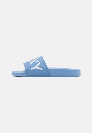 Sandale slide bleue avec semelle matelassée et large bride présentant des lettres blanches stylisées sur un fond clair uni.