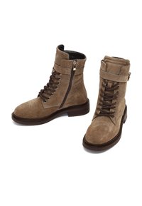 Bottes chevilles en daim marron avec un bout rond, un laçage à l'avant, une fermeture éclair sur le côté et une sangle avec une boucle sur le haut de la tige. Semelle à texture bois.