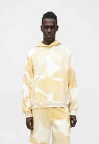 Sweatshirt com capuz creme e amarelo com padrões abstratos, material macio, bolso canguru, capuz com cordão, combinado com calções a condizer.