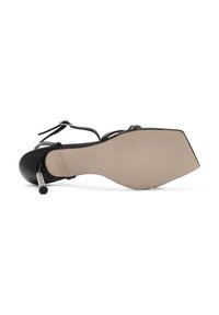 Zwarte hoge hak schoen met een spitse neus en enkelbandjes, voorzien van een glanzende afwerking en een geprofileerde beige zool. Decoratieve metalen accenten aanwezig.