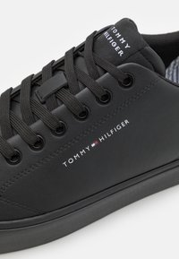 Czarne skórzane sneakersy z okrągłym noskiem, teksturowaną powierzchnią, czarnymi sznurowadłami, metalowymi oczkami i białym detalem logo po boku.