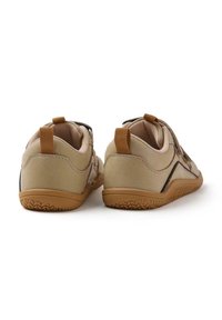 Scarpe beige chiaro con materiale testurizzato, suole in gomma marrone a contrasto e un pratico occhiello sul retro per indossarle facilmente. Design minimalista senza logo visibile.