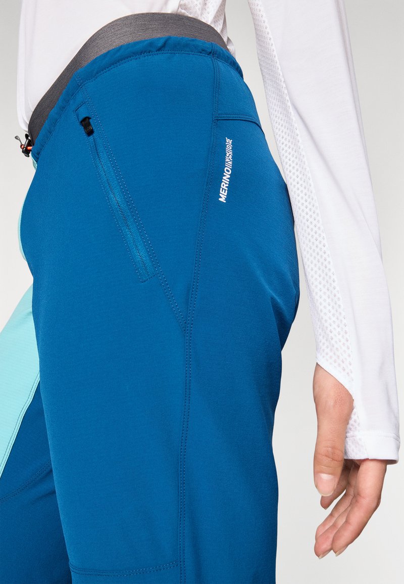 Blaue Wanderhose mit grauem Bund, ausgestattet mit einer Reißverschlusstasche und kontrastierenden hellblauen Akzenten, aus einem glatten, dehnbaren Material gefertigt.