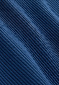 Material albastru cu textură diagonală în relief, evidențiind modelul detaliat de tricot și umbre subtile create de pliurile materialului.