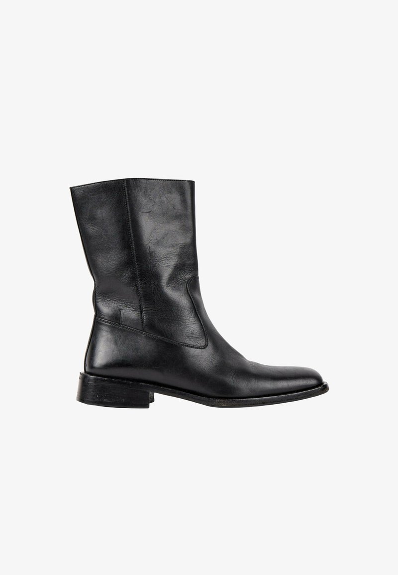 Botte noire en cuir mi-mollet avec un bout arrondi, un talon bas et des coutures apparentes sur fond blanc.
