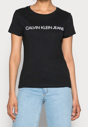 Black cotton t-shirt featuring a crew neck and short sleeves, with "CALVIN KLEIN JEANS" printed in white on the front.