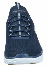 Baskets de sport Skechers avec une tige en mesh bleu marine, des lacets élastiques et une semelle en caoutchouc blanche avec des détails texturés.