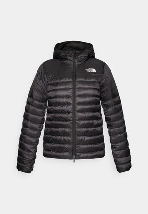 Fekete párnázott dzseki kapucnival, cipzáras záródással, vízszintesen steppelt kialakítással és kiemelkedő logóval a bal mellkas területen.