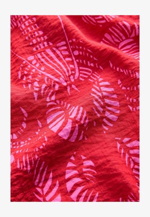 Tissu rouge avec un motif à motifs de feuilles roses, présentant une surface texturée et un contraste de couleurs vives.