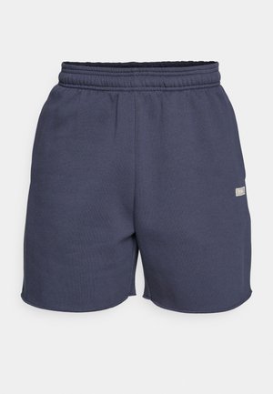 Temno modri hlače s spuščenim pasom, narejene iz mehkega blaga z gladko teksturo, z majhnim logotipom na strani.