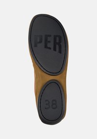 Sula av en sko med en svart strukturerad gummiyta med ingraverad text "PER" och storlek "38". Det omgivande området är brunt.