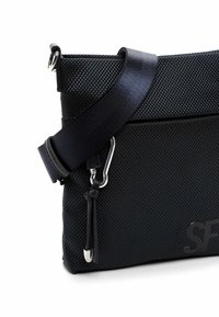 Borsa a tracolla nera realizzata in tessuto testurizzato, con una tracolla liscia, hardware in argento e un dettaglio logo sulla parte anteriore.