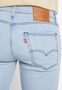 Světle modré džíny vyrobené z denimu s koženou cedulkou na pásku. Obsahují klasické zadní kapsy a červenou cedulku Levi's. Prošívání v kontrastní barvě.