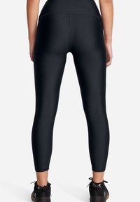 Leggings negros ajustados con una cintura alta, hechos de un material suave y elástico. Tienen costuras planas y un largo recortado, combinados con zapatillas negras.