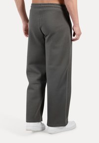 Gray sweatpants made of soft fabric, featuring a relaxed fit, elastic waistband, and side pockets, paired with white sneakers.