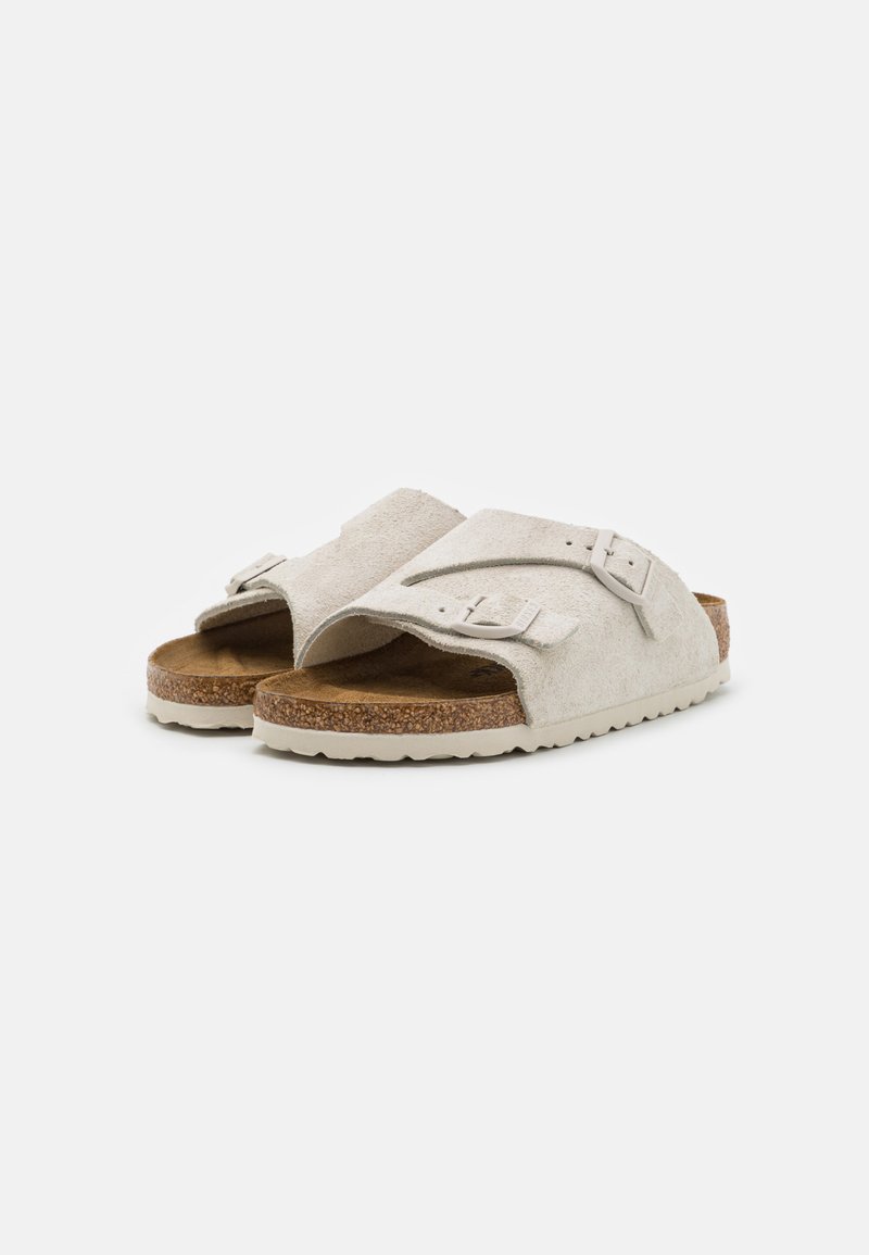 Helle graue Wildledersandalen mit offenem Zehenbereich, ausgestattet mit einem strukturierten Korkfußbett und einer leichten Gummisohle, ergänzt durch einen verstellbaren Riemen.