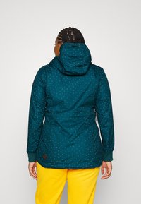 Teal waterproof jacket with a hood, featuring a dotted pattern in various colors. Includes a drawstring at the neck and elastic cuffs.